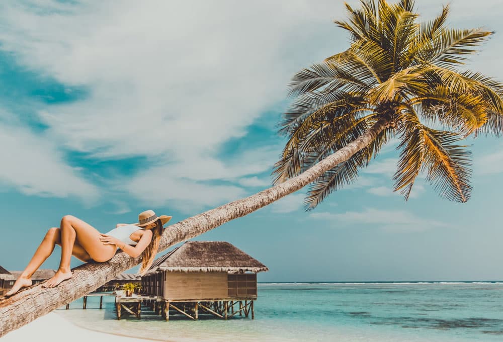 woman in bikini lying on tree maldives holiday